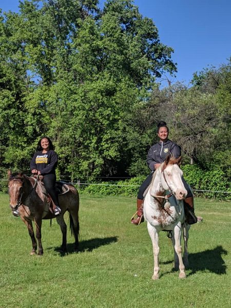 two girls riding horses in field